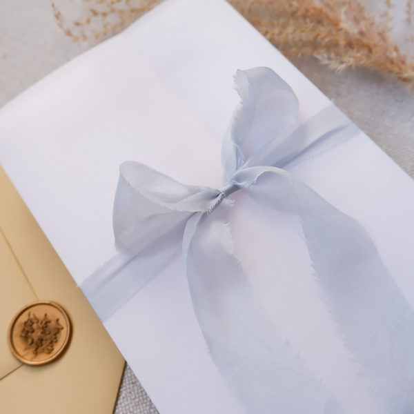 Seidenband Hochzeitseinladungen: Schleife aus Seidenband um Einladungskarte mit dekorativen Elementen